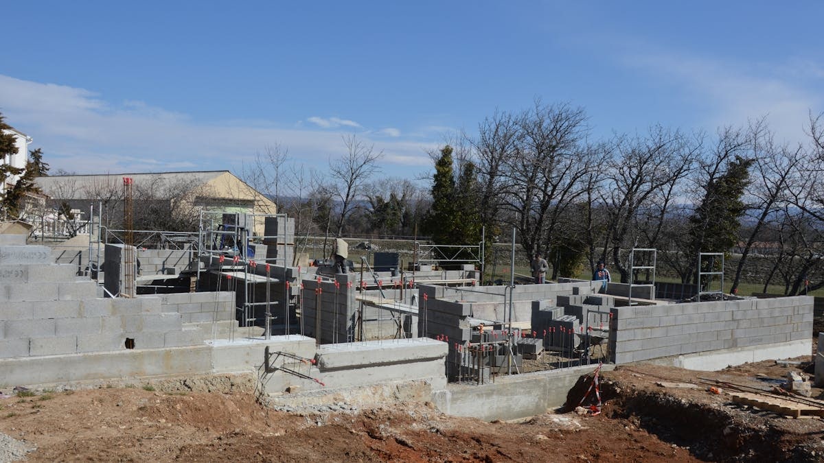 Outdoor construction site showing cinder block walls and scaffolding under a clear sky.